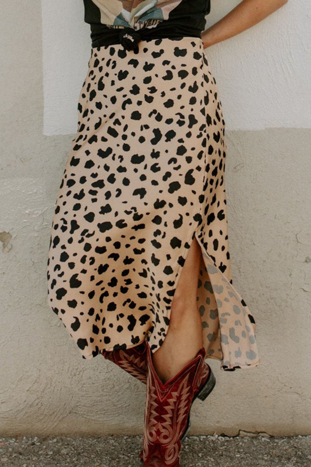 Slit printed midi skirt with black spot pattern and side slit, worn with brown cowboy boots.