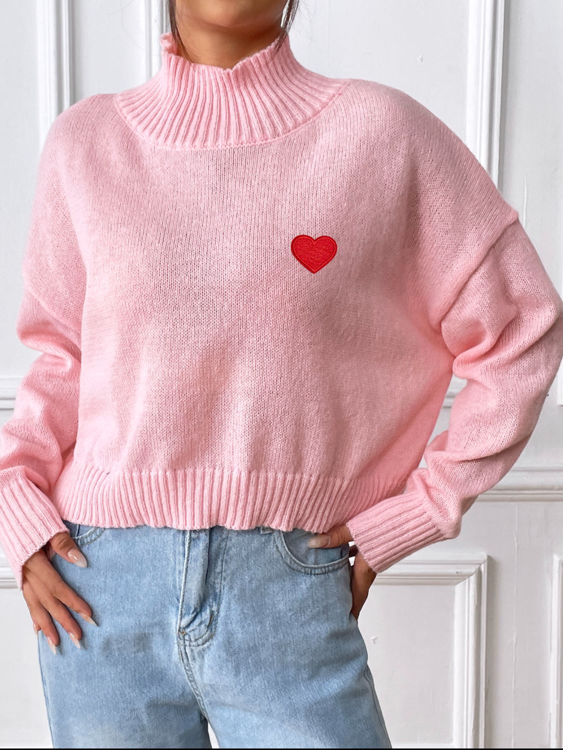 Heart turtleneck long sleeve sweater in pink with red heart emblem.